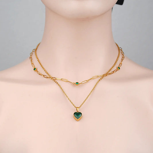 Front view of a model wearing the MEHRZEB emerald heart double chain layered necklace.
