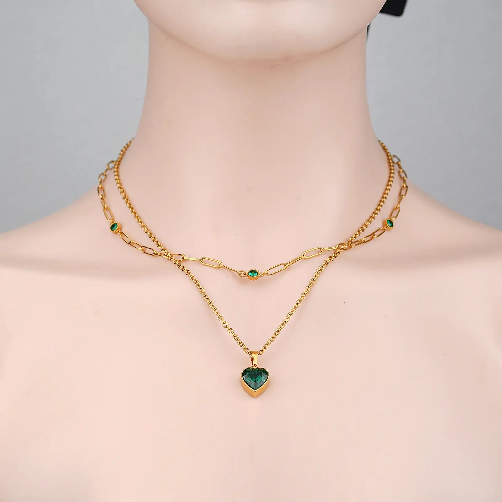 Front view of a model wearing the MEHRZEB emerald heart double chain layered necklace.
