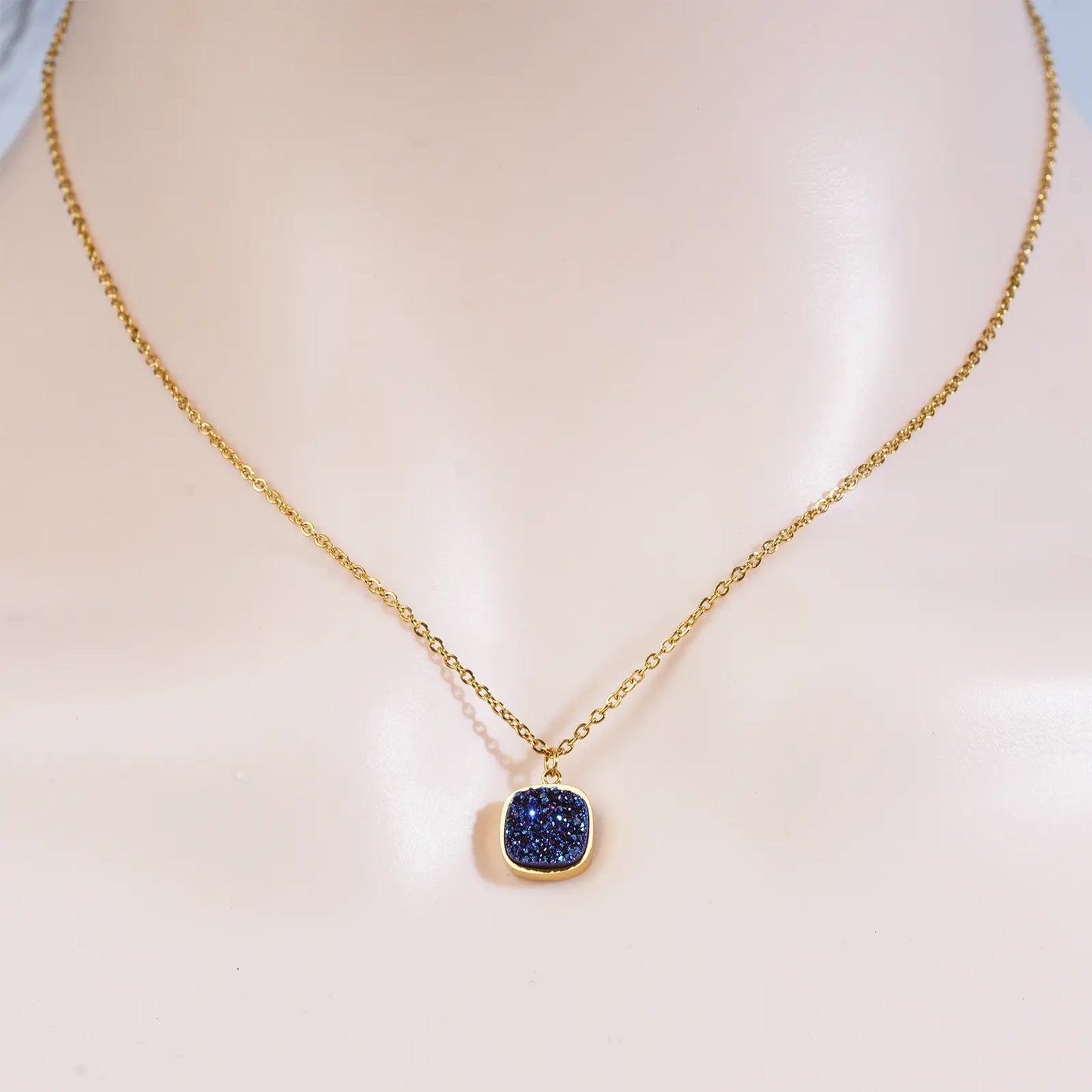 Front view of a model wearing the MEHRZEB midnight azure gold pendant necklace showing how it lays on the neck.