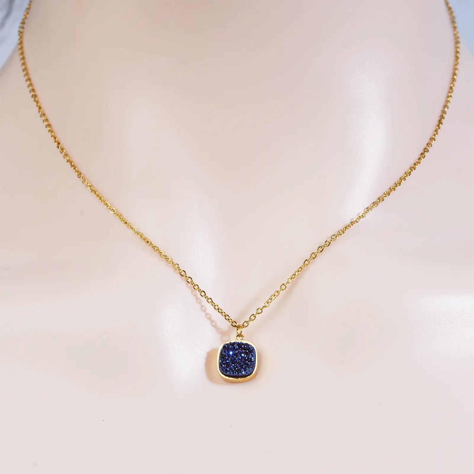 Front view of a model wearing the MEHRZEB midnight azure gold pendant necklace showing how it lays on the neck.