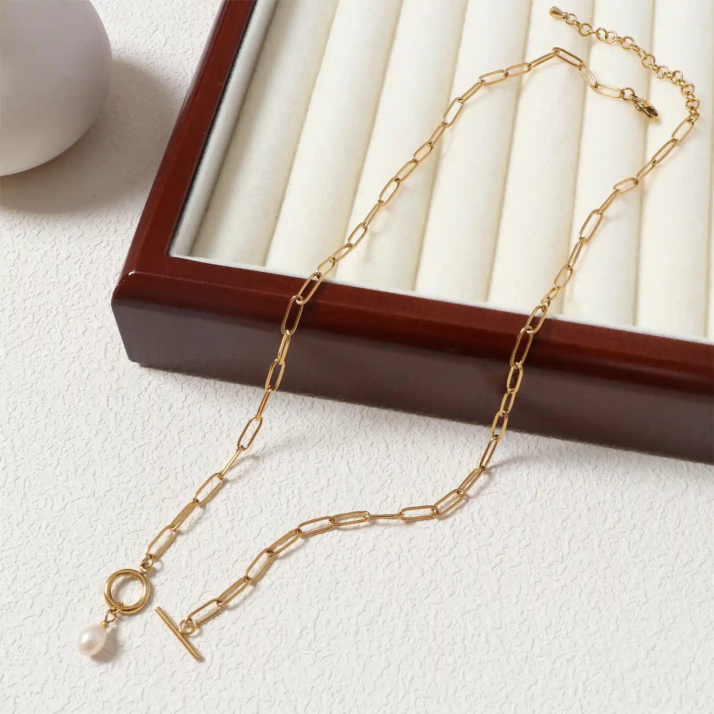 Flat lay aesthetic view of the MEHRZEB waterproof 18k gold paperclip chain and natural pearl.