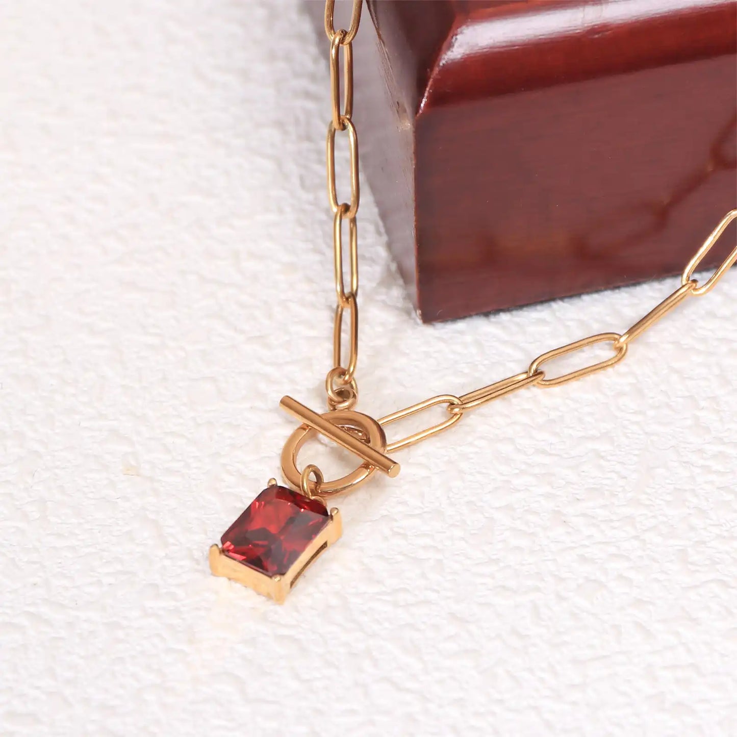 Macro close up of the emerald-cut ruby red zircon stone and 18k gold PVD toggle clasp by MEHRZEB.